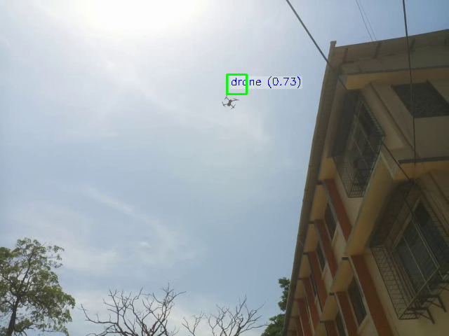 A small drone against a bright, hazy sky beside a building